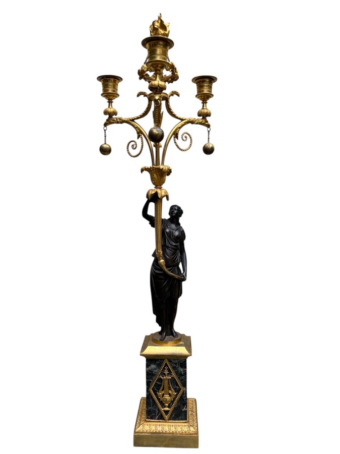 An elegant pair of candelabras in finely chased, gilded and patinated bronze. The shaft is adorned with an antique draped female figure, resting on a green marble base. In the Louis XVI style, these pieces date from the early 19th century. 
