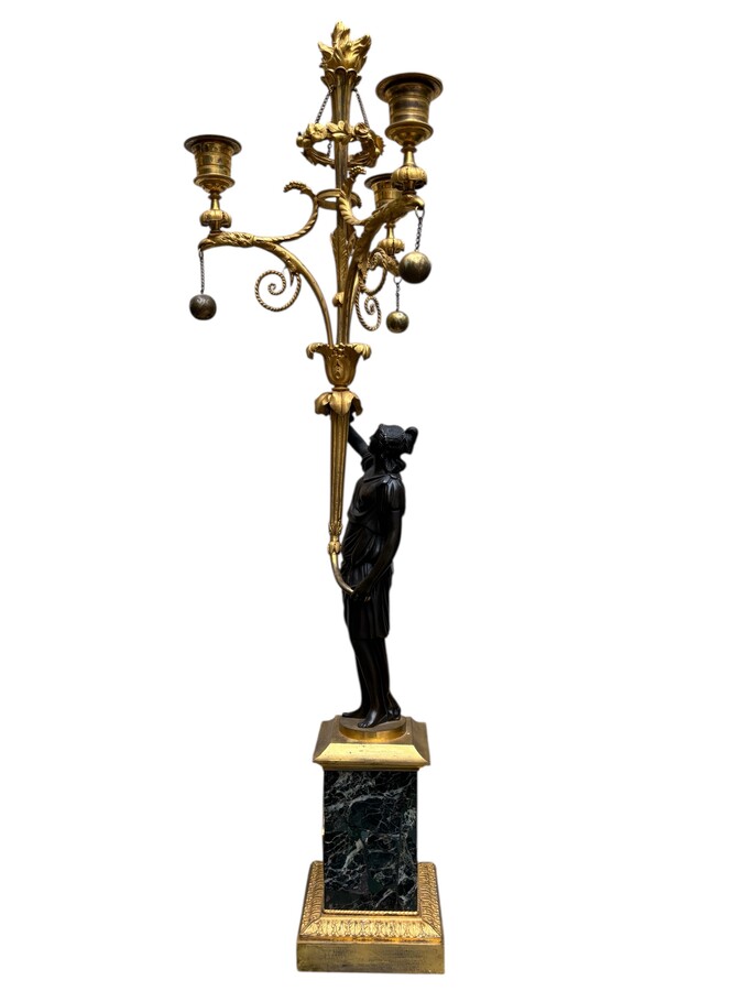 An elegant pair of candelabras in finely chased, gilded and patinated bronze. The shaft is adorned with an antique draped female figure, resting on a green marble base. In the Louis XVI style, these pieces date from the early 19th century. 