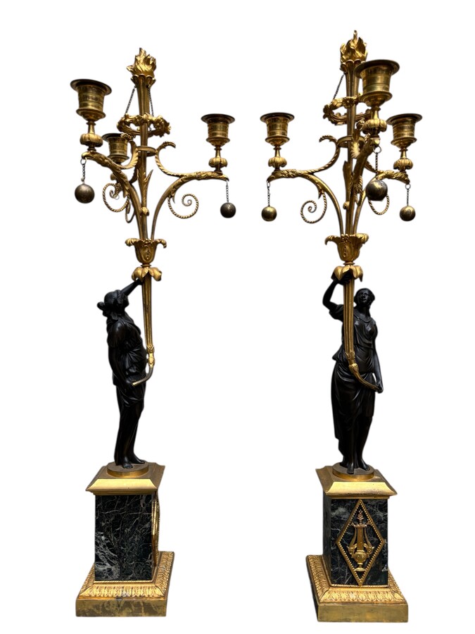 An elegant pair of candelabras in finely chased, gilded and patinated bronze. The shaft is adorned with an antique draped female figure, resting on a green marble base. In the Louis XVI style, these pieces date from the early 19th century. 