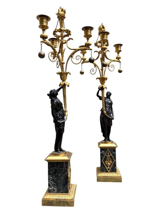 An elegant pair of candelabras in finely chased, gilded and patinated bronze. The shaft is adorned with an antique draped female figure, resting on a green marble base. In the Louis XVI style, these pieces date from the early 19th century. 