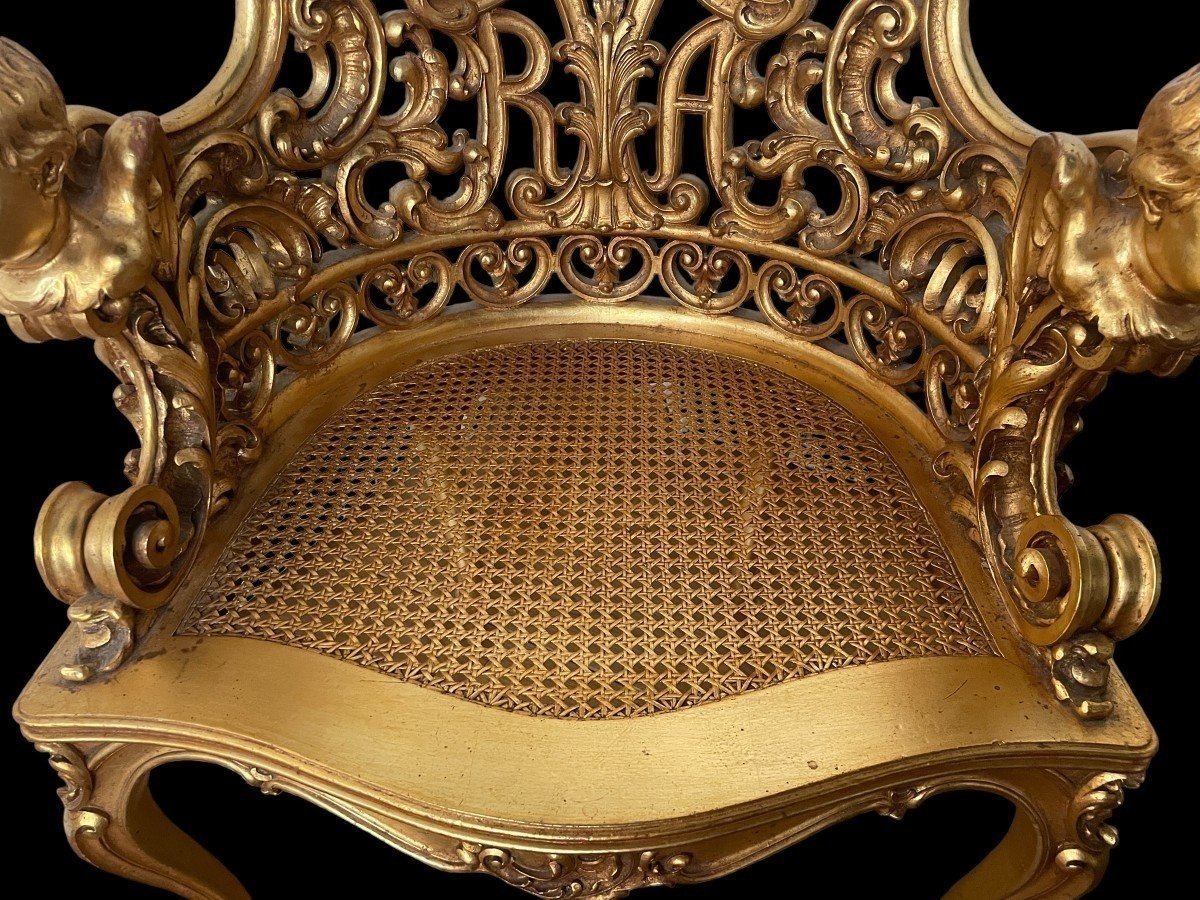 An honorary seat with angel heads in gilt wood 19th century. Special seat decorated with scrolls, ornaments and angel heads in gilt wood. Seat in wicker. Dimensions : Height : 93 cm Width : 71 cm Depth : 58 cm Seat height : 39 cm Decorative chair