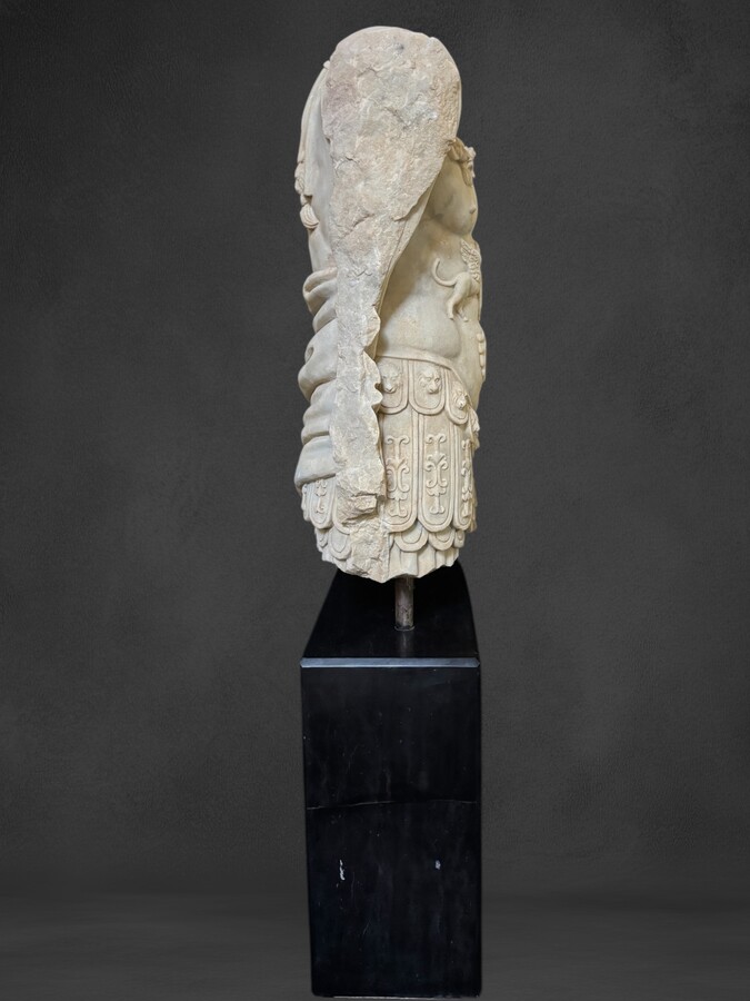 An impressive sculpture of a Roman torso in white marble, exuding the power and beauty of classical antiquity. The detailed breastplate is richly decorated with hand-carved mythological motifs. 