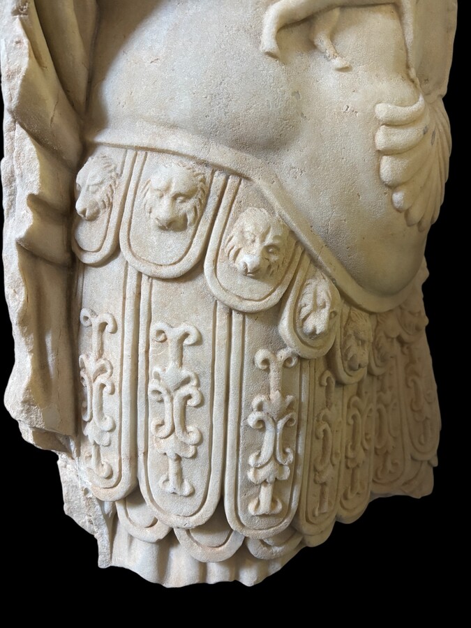 An impressive sculpture of a Roman torso in white marble, exuding the power and beauty of classical antiquity. The detailed breastplate is richly decorated with hand-carved mythological motifs. 