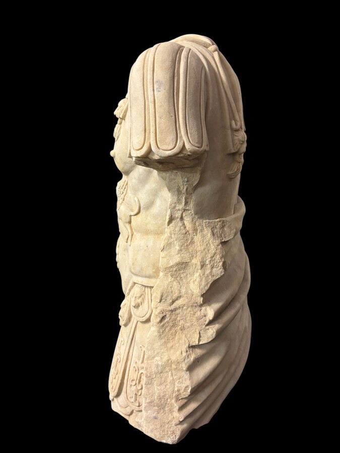 An impressive sculpture of a Roman torso in white marble, exuding the power and beauty of classical antiquity. The detailed breastplate is richly decorated with hand-carved mythological motifs. 