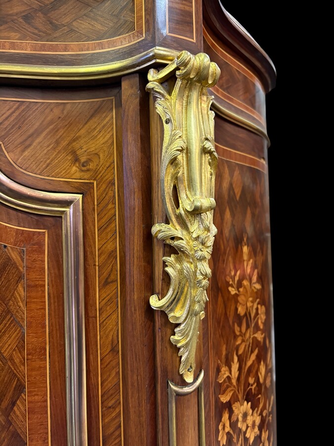 Attractive sideboard with a slightly curved front in rosewood veneer, rosewood and various precious woods. Central door and curved sides decorated with a floral bouquet, interior with two shelves, richly decorated with gilded bronze fittings. 