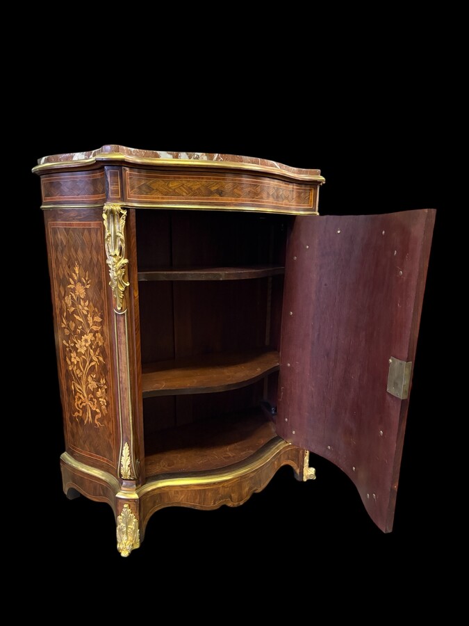 Attractive sideboard with a slightly curved front in rosewood veneer, rosewood and various precious woods. Central door and curved sides decorated with a floral bouquet, interior with two shelves, richly decorated with gilded bronze fittings. 