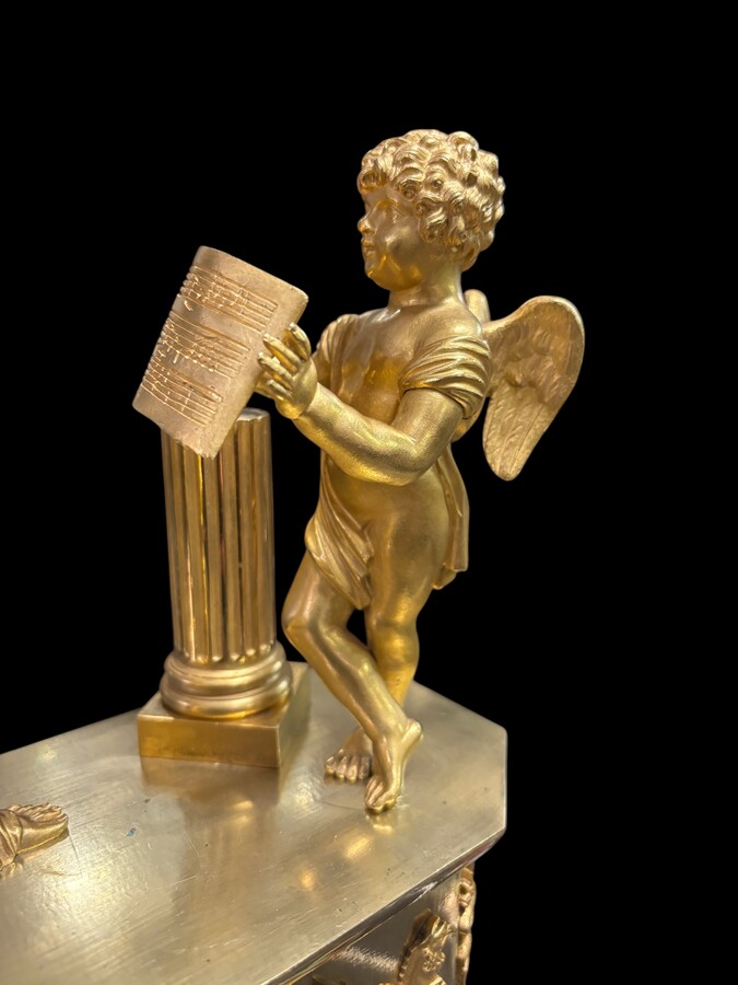 Beautiful Empire period clock in matt and bright gilt bronze depicting a lady playing guitar with an angel. In very good condition, the movement has not been checked. The balance wheel is present. Dimensions: Width: 31.5 cm Height: 43 cm Depth : 13 cm