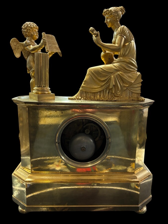 Beautiful Empire period clock in matt and bright gilt bronze depicting a lady playing guitar with an angel. In very good condition, the movement has not been checked. The balance wheel is present. Dimensions: Width: 31.5 cm Height: 43 cm Depth : 13 cm
