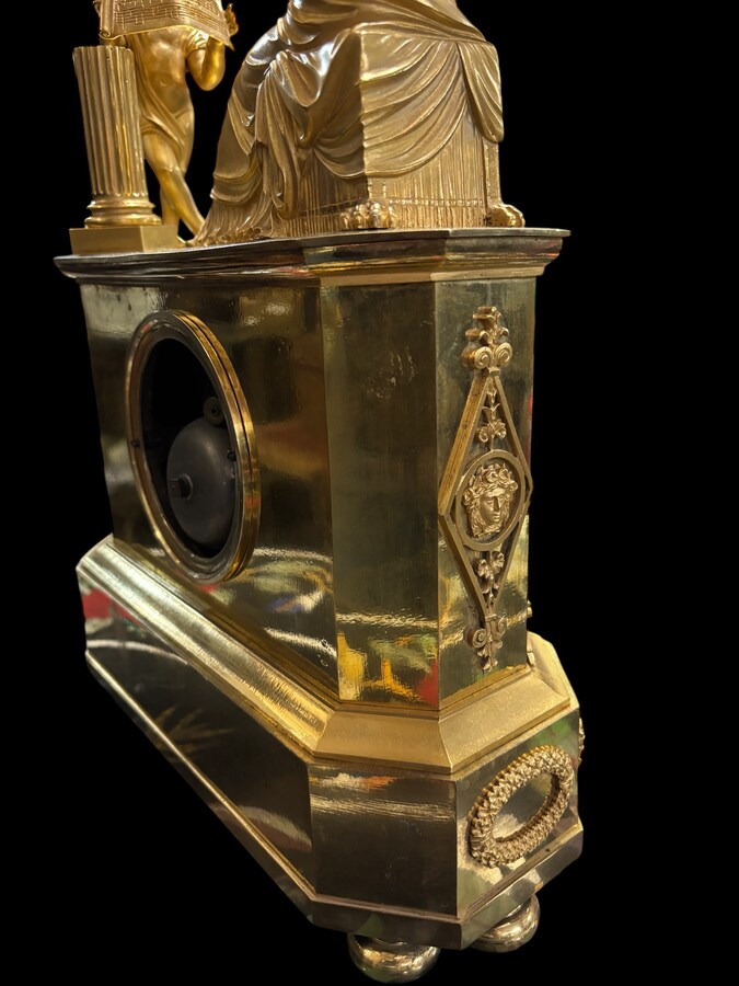 Beautiful Empire period clock in matt and bright gilt bronze depicting a lady playing guitar with an angel. In very good condition, the movement has not been checked. The balance wheel is present. Dimensions: Width: 31.5 cm Height: 43 cm Depth : 13 cm