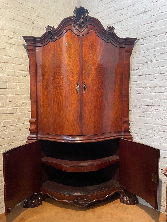 Beautiful large Dutch mahogany corner cupboard from the 18th century. Curved corner cupboard with 4 doors and 4 small drawers inside and standing on large claw feet. The cabinet is in good condition with normal signs of use.