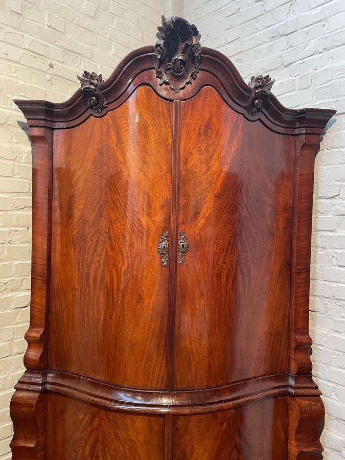 Beautiful large Dutch mahogany corner cupboard from the 18th century. Curved corner cupboard with 4 doors and 4 small drawers inside and standing on large claw feet. The cabinet is in good condition with normal signs of use.