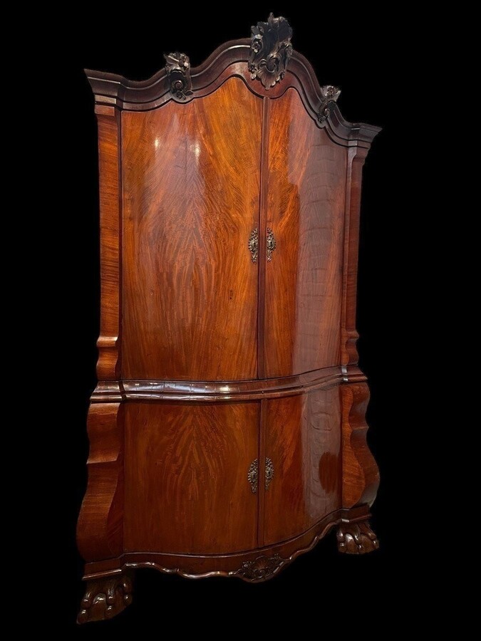 Beautiful large Dutch mahogany corner cupboard from the 18th century. Curved corner cupboard with 4 doors and 4 small drawers inside and standing on large claw feet. The cabinet is in good condition with normal signs of use.