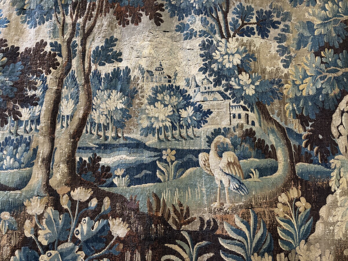 Beautiful large wool tapestry 17th century. Representation of a castle, a village with churches , birds , a river with waterfall in a landscape with large trees , shrubs and flowers. The tapestry has a wide and beautiful border decorated with flowers and 