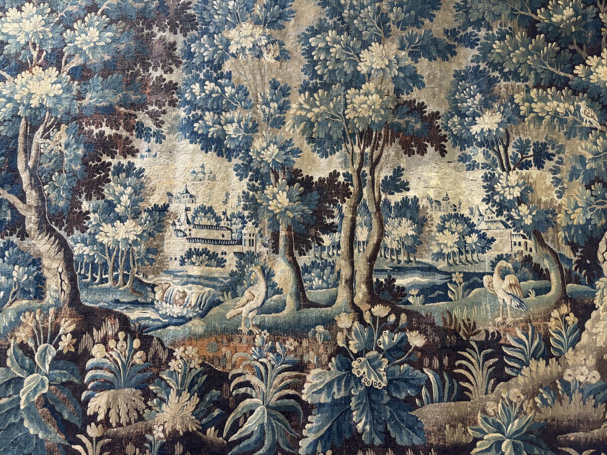 Beautiful large wool tapestry 17th century. Representation of a castle, a village with churches , birds , a river with waterfall in a landscape with large trees , shrubs and flowers. The tapestry has a wide and beautiful border decorated with flowers and 