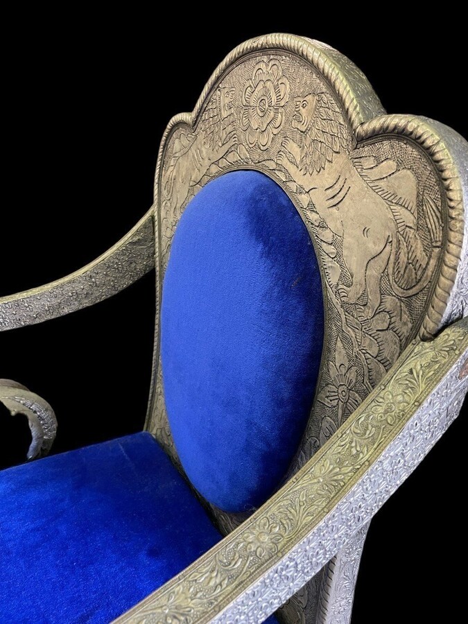 Decorative Orientalist armchair covered with tooled metal. The armchair is decorated with lions serving as armrests and is completely covered with a thin layer of silver metal decorated with flowers and ornaments and colourful fabric
