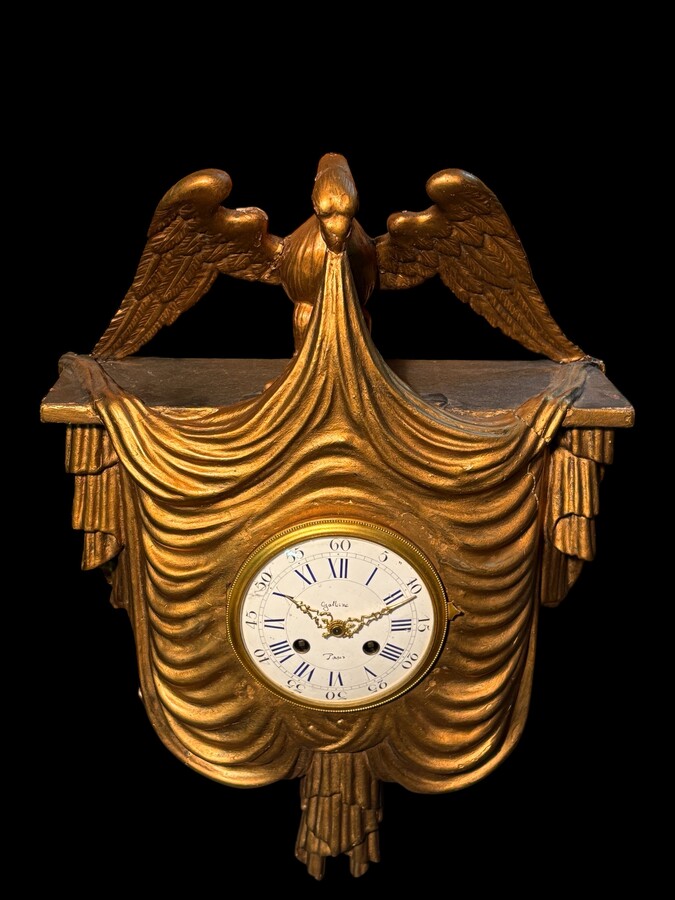 Elegant 19th-century gilt wooden eagle clock with drapery Decorative clock in gilt wood and paste depicting an eagle carrying a large drapery that falls to the left and right of the dial. In normal condition with a few small flaws on the wood.
