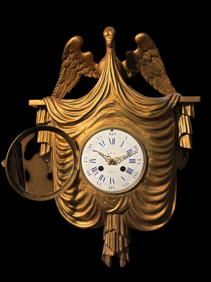 Elegant 19th-century gilt wooden eagle clock with drapery Decorative clock in gilt wood and paste depicting an eagle carrying a large drapery that falls to the left and right of the dial. In normal condition with a few small flaws on the wood.
