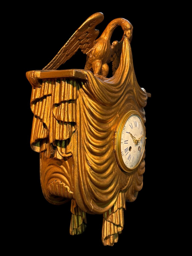 Elegant 19th-century gilt wooden eagle clock with drapery Decorative clock in gilt wood and paste depicting an eagle carrying a large drapery that falls to the left and right of the dial. In normal condition with a few small flaws on the wood.