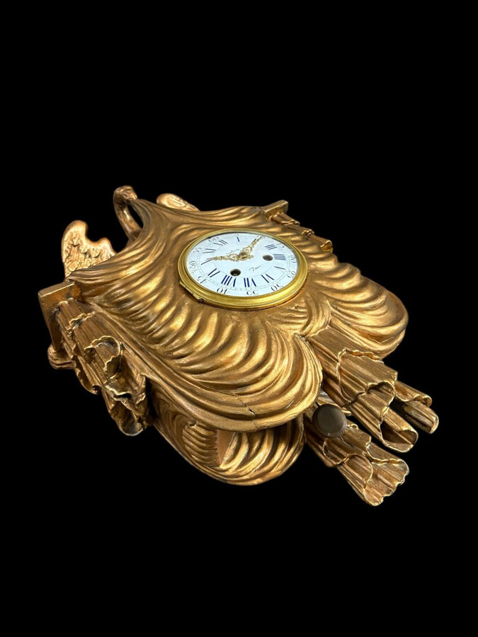 Elegant 19th-century gilt wooden eagle clock with drapery Decorative clock in gilt wood and paste depicting an eagle carrying a large drapery that falls to the left and right of the dial. In normal condition with a few small flaws on the wood.