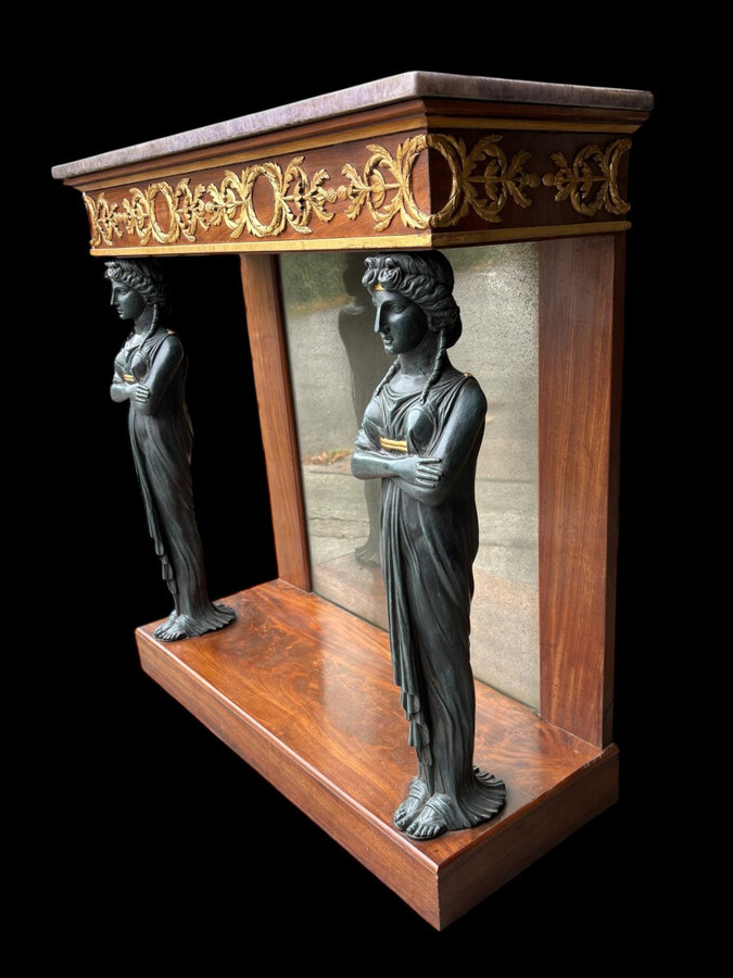 Elegant Empire-style mahogany console table, 19th century. Decorative Empire-style console table adorned with two large patinated female figures, gilded decorations, a mirror at the back and a special marble top.
