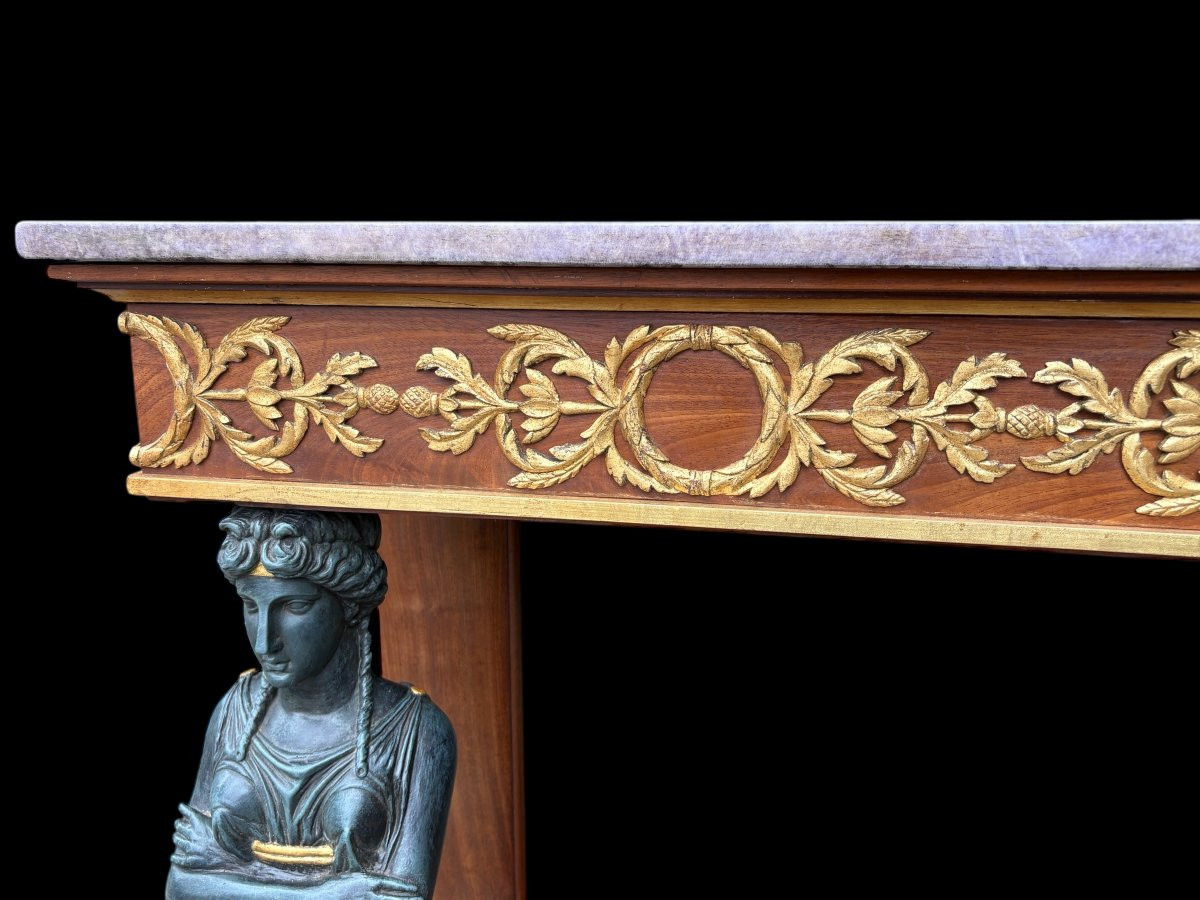 Elegant Empire-style mahogany console table, 19th century. Decorative Empire-style console table adorned with two large patinated female figures, gilded decorations, a mirror at the back and a special marble top.