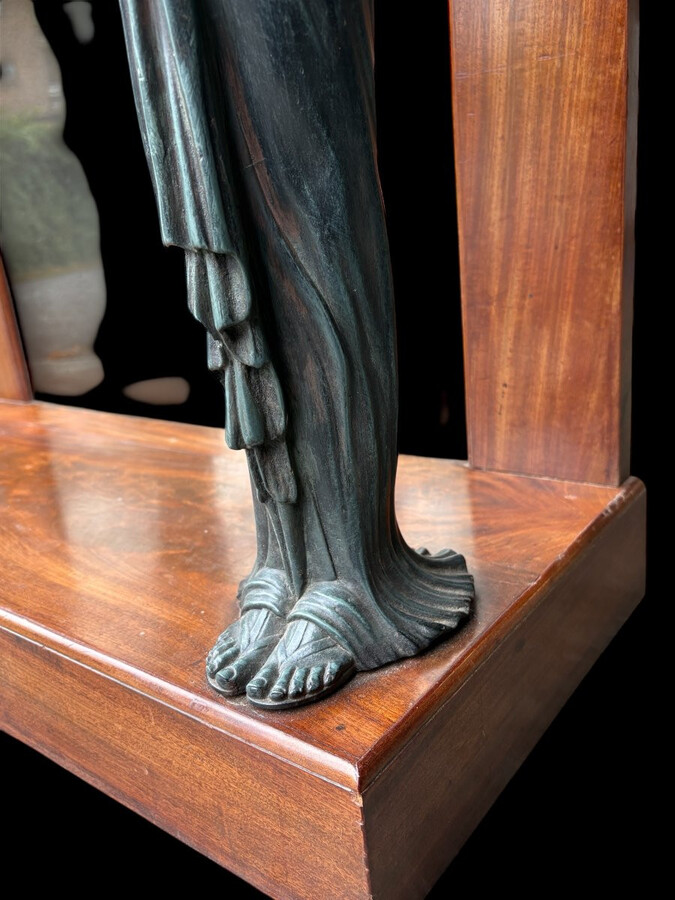 Elegant Empire-style mahogany console table, 19th century. Decorative Empire-style console table adorned with two large patinated female figures, gilded decorations, a mirror at the back and a special marble top.
