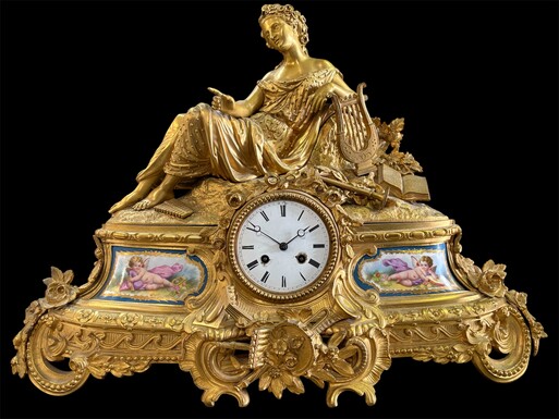 Elegant gilt bronze clock / Sèvres, 19th century Clock depicting a reclining lady with musical instruments and Sèvres porcelain plates Pendulum and bell present, movement not verified. Dimensions : Width: 57 cm Height: 45 cm Depth: 16 cm