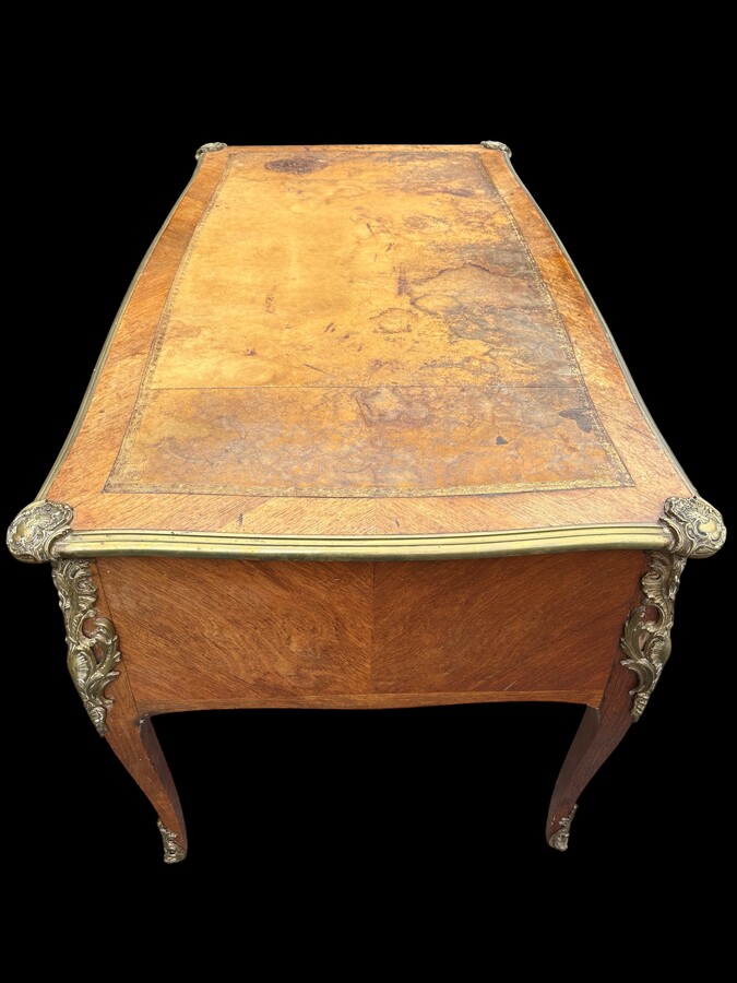 Elegant Louis XV-style veneered wooden desk, 1900 The desk features 5 drawers, bronze fittings and decorations, and a brown leather top. The desk is in good condition but requires refurbishment. Dimensions: Width: 140 cm Height: 76 cm