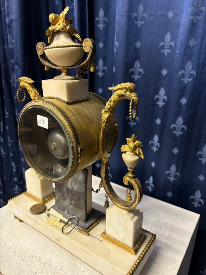 Elegant Louis XVI style clock from the 18th century. Beautiful 18th century marble and gilt bronze mantel clock decorated with vases of flowers, ornaments, griffin heads and bronze girlandes. The pendulum and key are present. 18thC.