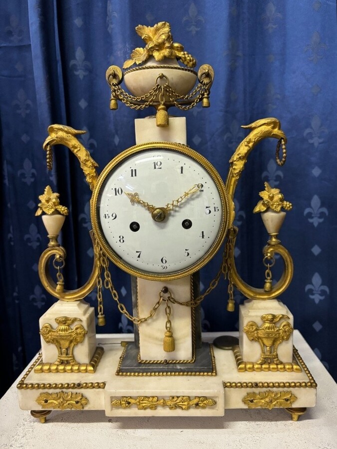 Elegant Louis XVI style clock from the 18th century. Beautiful 18th century marble and gilt bronze mantel clock decorated with vases of flowers, ornaments, griffin heads and bronze girlandes. The pendulum and key are present. 18thC.