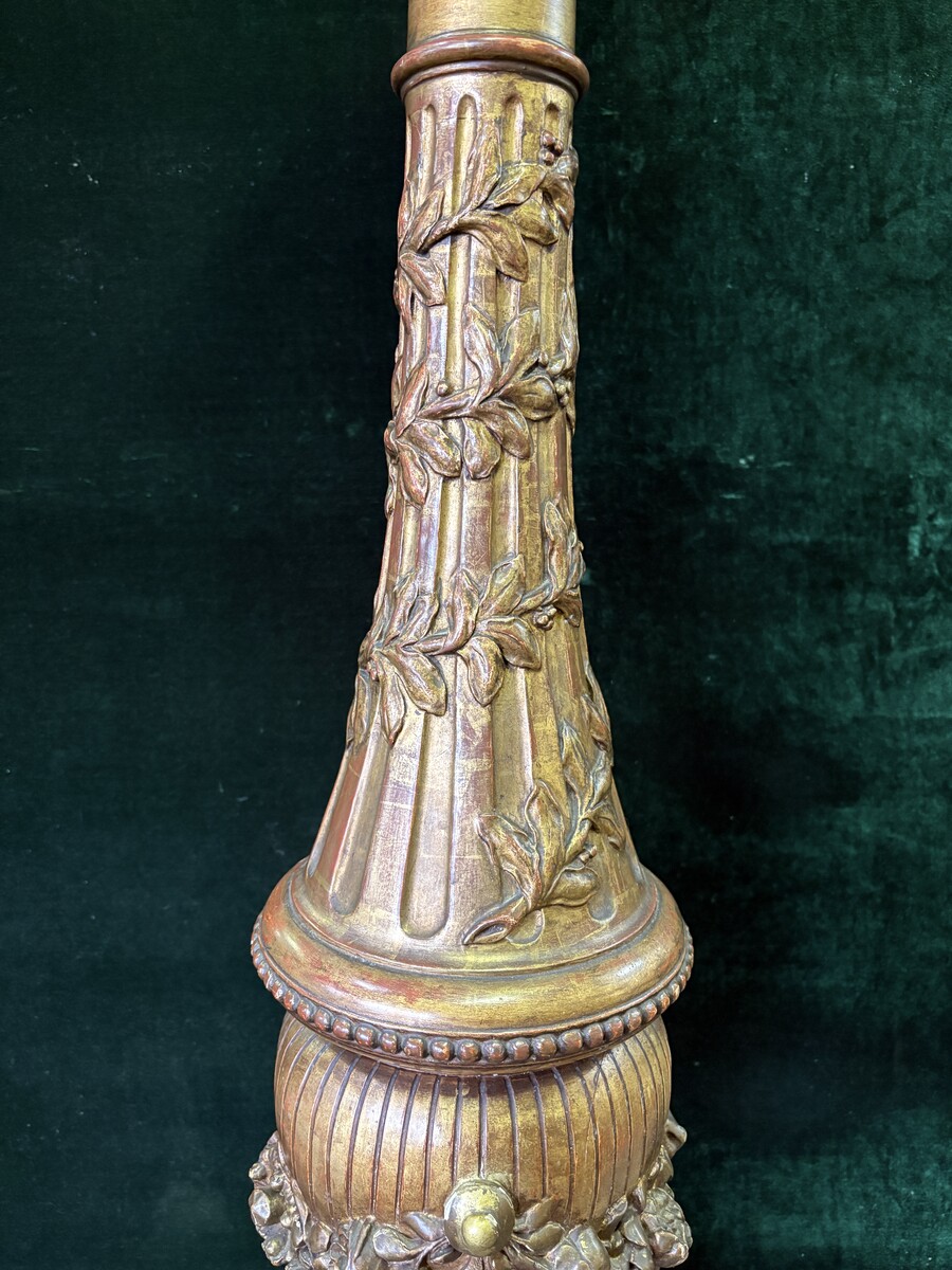 Large 19th-century gilded wooden candelabra (163 cm) Decorative candelabra with a stem, adorned with motifs, tendrils, garlands, French lilies, drapery and tassels, resting on three large legs decorated with mythological fish and scrolls.