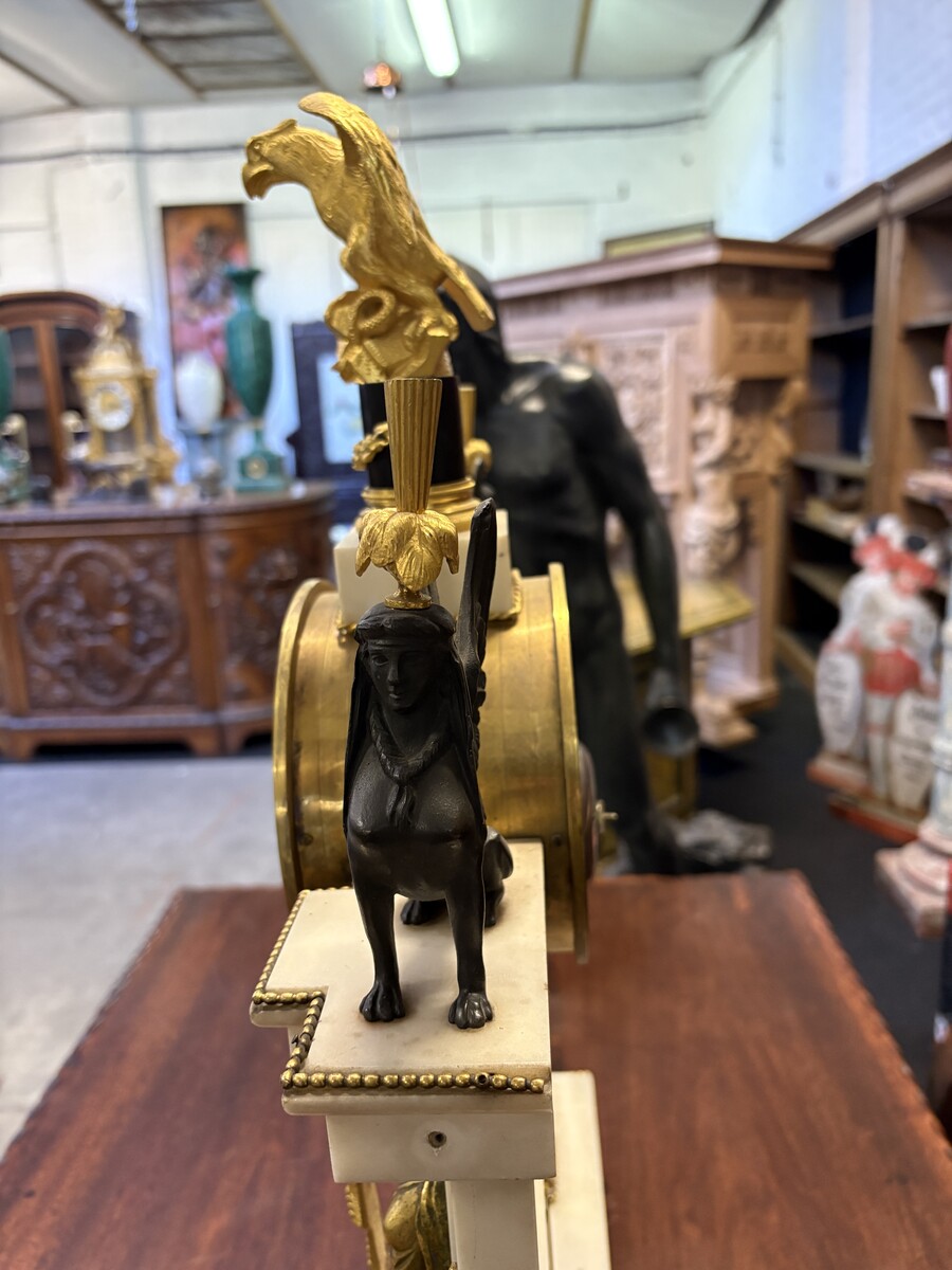 Large Empire-style portico clock (64.5 cm), 19thC. Large clock featuring two marble columns adorned with two caryatids, rosettes, drapery, decorative motifs, two patinated and gilded sphinxes, and an eagle at the top. Sun dial and key included; move