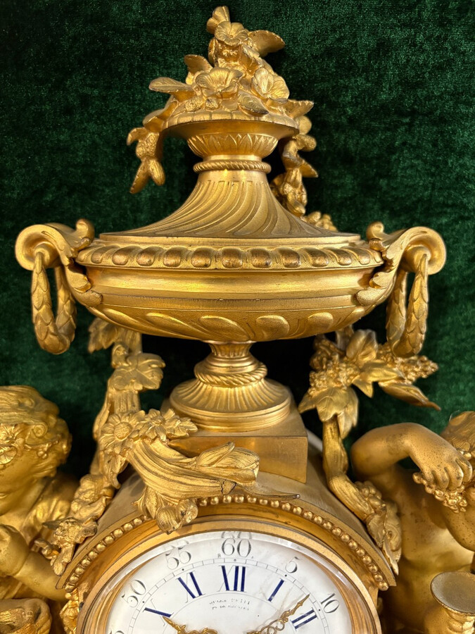 Large gilt bronze clock set. Paris, 19th century. A beautiful large clock with four cherubs and very fine gilt bronze decorations, as well as two candlesticks representing two large cherubs carrying a torch with six candlesticks.