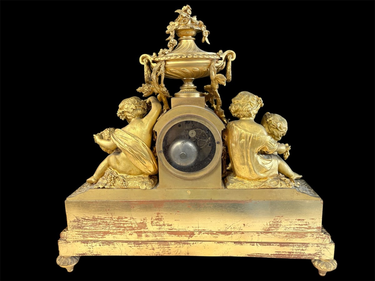 Large gilt bronze clock set. Paris, 19th century. A beautiful large clock with four cherubs and very fine gilt bronze decorations, as well as two candlesticks representing two large cherubs carrying a torch with six candlesticks.