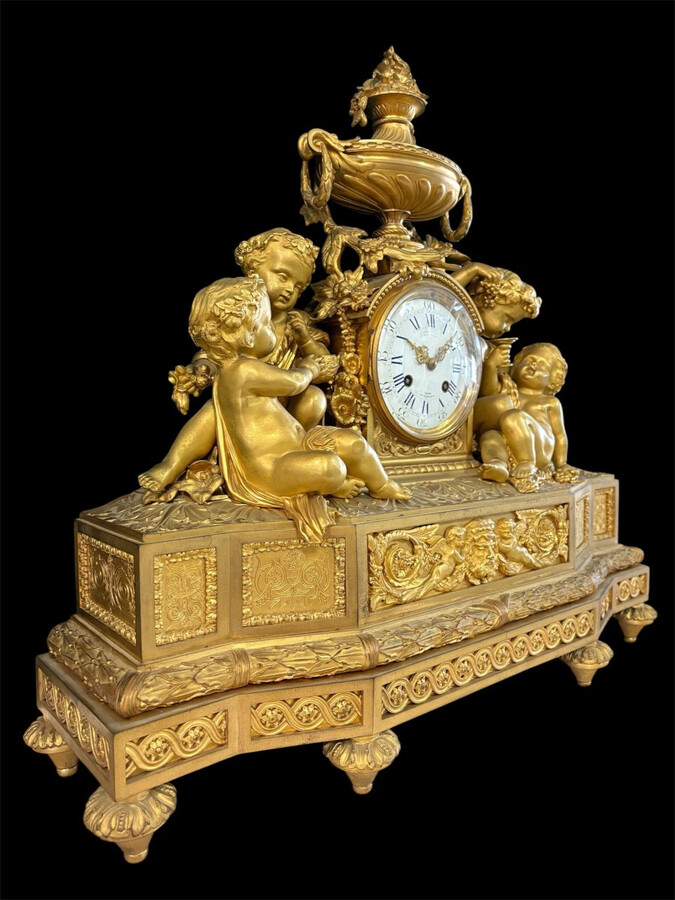 Large gilt bronze clock set. Paris, 19th century. A beautiful large clock with four cherubs and very fine gilt bronze decorations, as well as two candlesticks representing two large cherubs carrying a torch with six candlesticks.