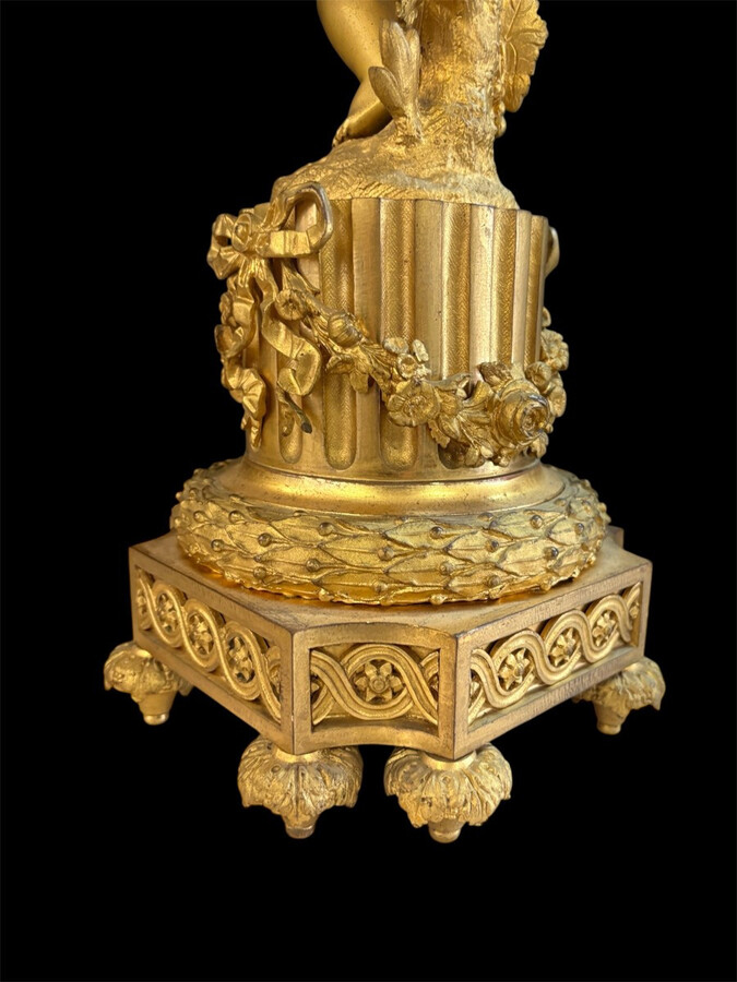 Large gilt bronze clock set. Paris, 19th century. A beautiful large clock with four cherubs and very fine gilt bronze decorations, as well as two candlesticks representing two large cherubs carrying a torch with six candlesticks.