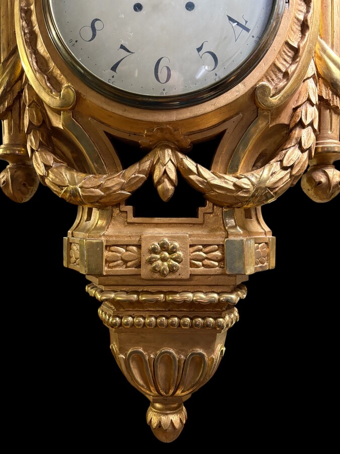 Large Swedish clock in gilded wood, Louis XVI style, 19th century Highly decorative clock in matt and shiny gold. Dimensions: Height: 97 cm Width: 49 cm Depth: 13 cm Key and pendulum present, mechanism to be checked. Attractive Swedish clock, circa 1860-1
