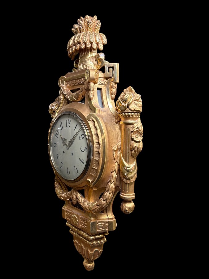 Large Swedish clock in gilded wood, Louis XVI style, 19th century Highly decorative clock in matt and shiny gold. Dimensions: Height: 97 cm Width: 49 cm Depth: 13 cm Key and pendulum present, mechanism to be checked. Attractive Swedish clock, circa 1860-1
