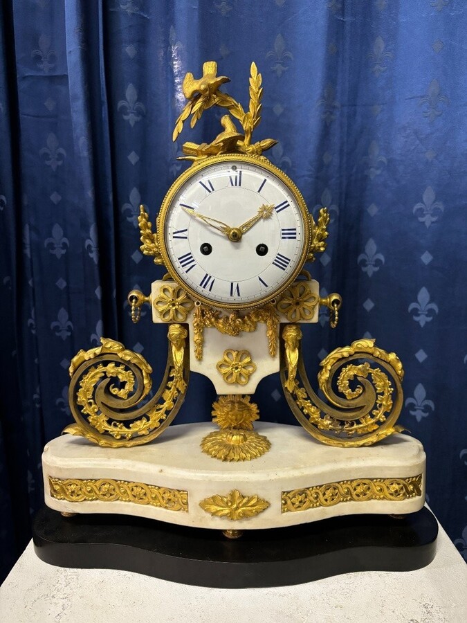 Nice Louis XVI style clock in marble and gilt bronze 18th century Elegant mantel clock decorated with gilt bronze ornaments, women's heads, birds, foliage and its original sundial. Minor old restoration to the marble base. Dimensions : Height: 41 cm