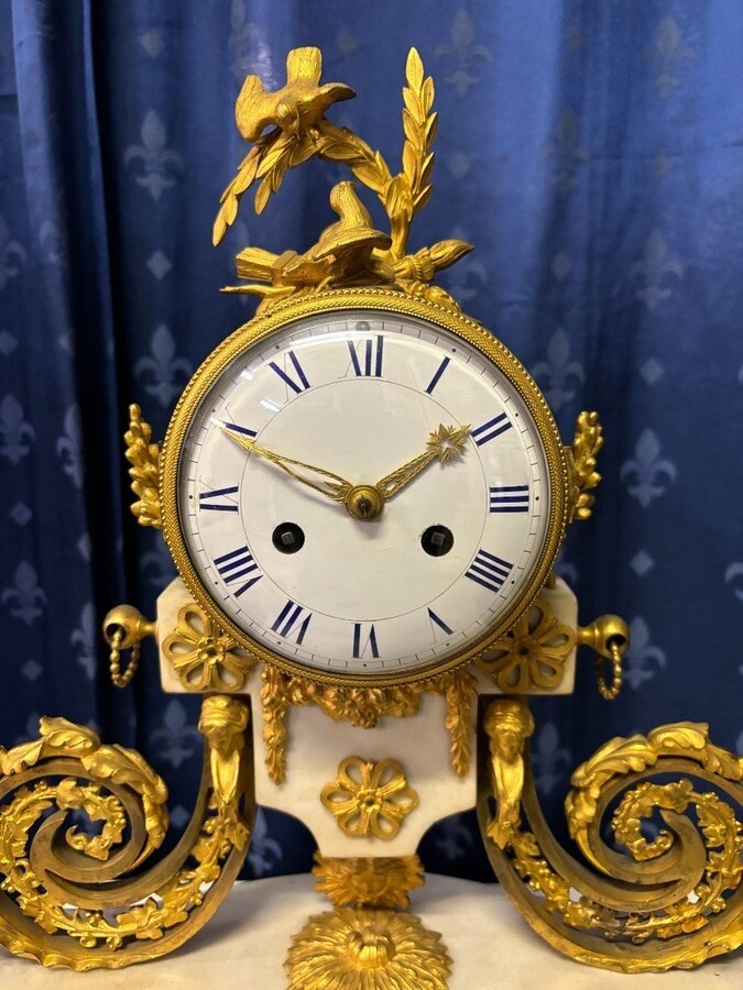 Nice Louis XVI style clock in marble and gilt bronze 18th century Elegant mantel clock decorated with gilt bronze ornaments, women's heads, birds, foliage and its original sundial. Minor old restoration to the marble base. Dimensions : Height: 41 cm