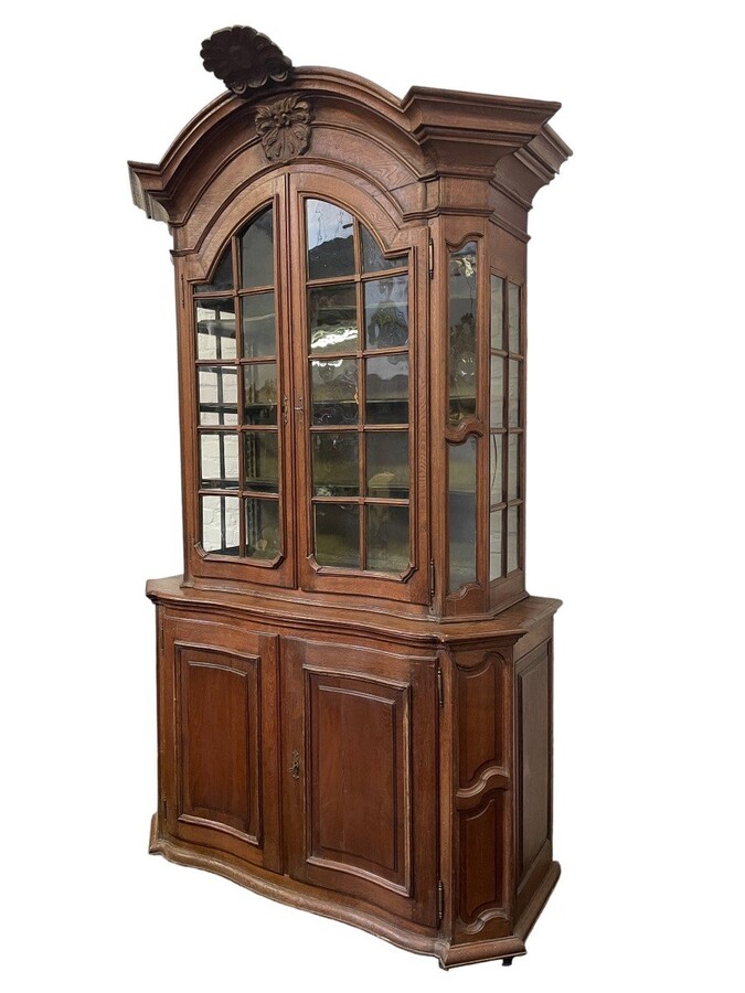 Oak 18th century display cabinet with 4 curved doors. Beautiful large 18th century Flemish display cabinet with curved fronts at top and bottom and a carved double shell at top and glass on the sides The cabinet is made up of 2 parts