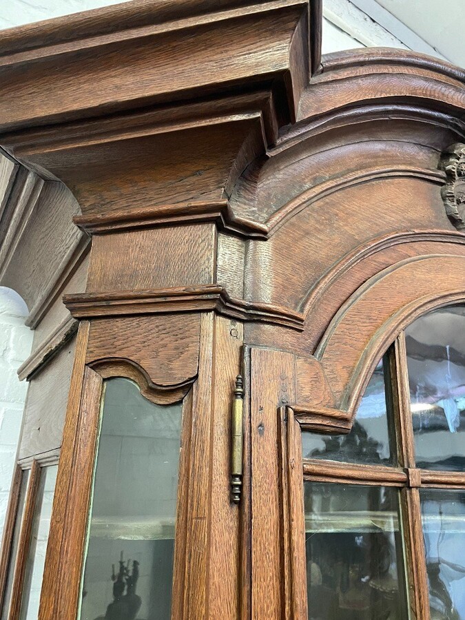 Oak 18th century display cabinet with 4 curved doors. Beautiful large 18th century Flemish display cabinet with curved fronts at top and bottom and a carved double shell at top and glass on the sides The cabinet is made up of 2 parts