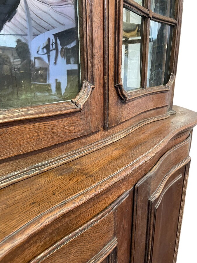 Oak 18th century display cabinet with 4 curved doors. Beautiful large 18th century Flemish display cabinet with curved fronts at top and bottom and a carved double shell at top and glass on the sides The cabinet is made up of 2 parts