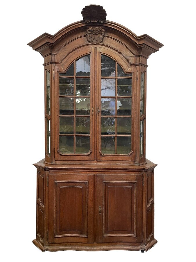 Oak 18th century display cabinet with 4 curved doors. Beautiful large 18th century Flemish display cabinet with curved fronts at top and bottom and a carved double shell at top and glass on the sides The cabinet is made up of 2 parts