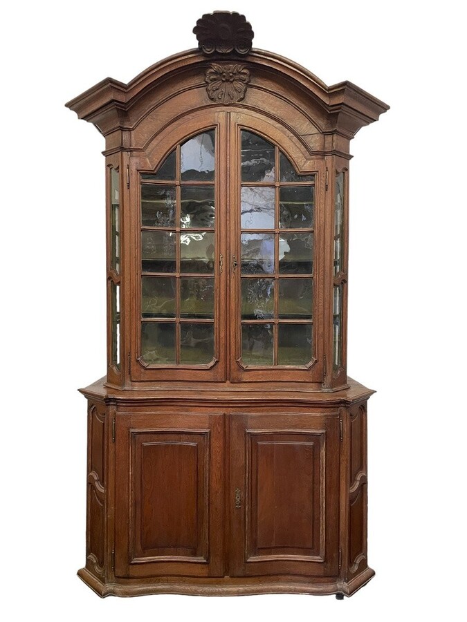 Oak 18th century display cabinet with 4 curved doors. Beautiful large 18th century Flemish display cabinet with curved fronts at top and bottom and a carved double shell at top and glass on the sides The cabinet is made up of 2 parts