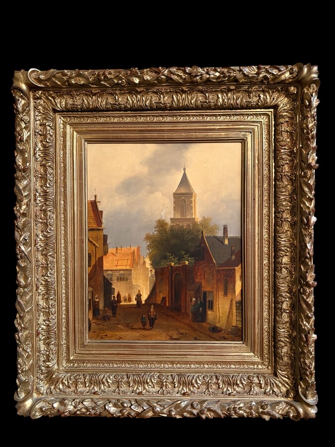 Painting ‘View of an Old Dutch Town’ oil on panel, 19th century Decorative painting in a large gilded frame depicting an old town, a street with old houses, a church, a gate with a municipal garden and various figures. 