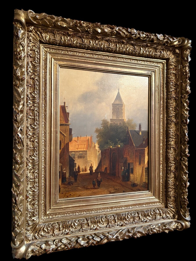 Painting ‘View of an Old Dutch Town’ oil on panel, 19th century Decorative painting in a large gilded frame depicting an old town, a street with old houses, a church, a gate with a municipal garden and various figures.
