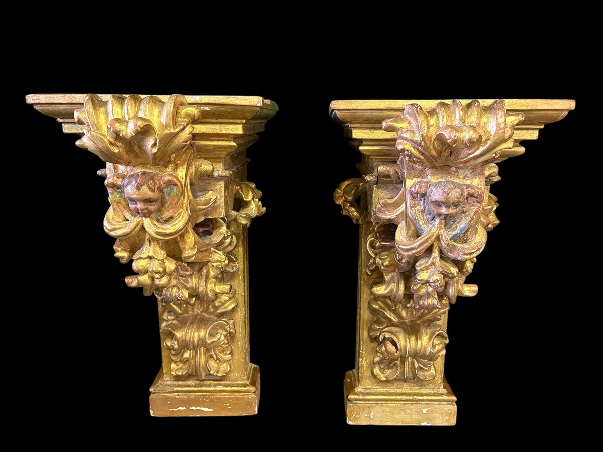 Pair of 17th-century Italian Baroque consoles. Decorative consoles carved in wood, gilded/polychrome, with garlands, fruit, angel heads and decorative ornaments. Ideal for creating a beautiful wall console. Both are in good condition, with normal signs of