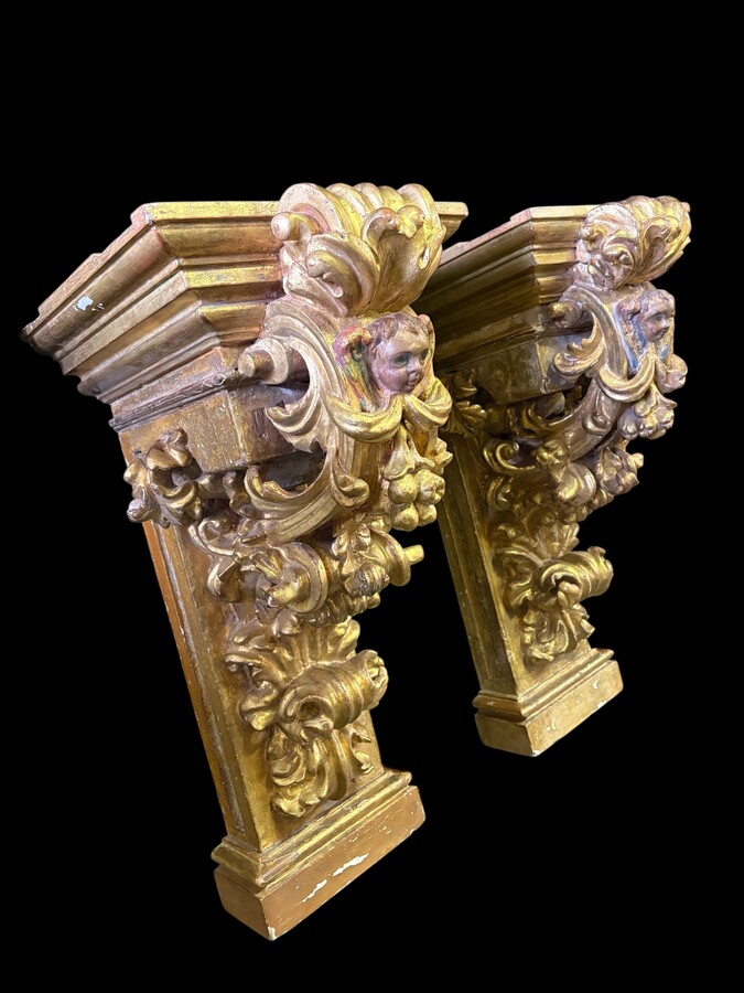 Pair of 17th-century Italian Baroque consoles. Decorative consoles carved in wood, gilded/polychrome, with garlands, fruit, angel heads and decorative ornaments. Ideal for creating a beautiful wall console. Both are in good condition, with normal signs of
