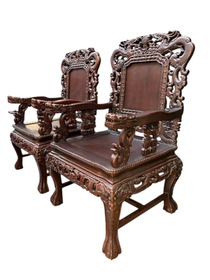 Pair of Asian solid wood armchairs, 20th century Decorative armchairs adorned with magnificent dragons and dragon heads as armrests. Dimensions: Height: 119 cm Width: 76 cm Depth: 67 cm Heavy solid wood armchairs in good condition, 20th century.